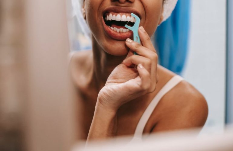chica utilizando hilo dental, uno de los tips para mantener tu salud bucodental