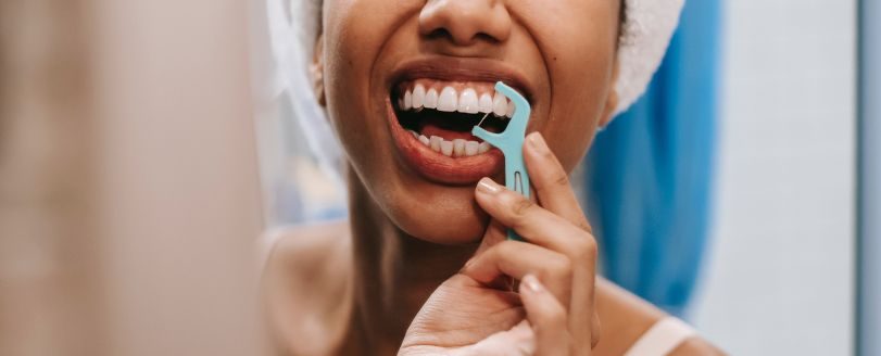 chica utilizando hilo dental, uno de los tips para mantener una buena salud bucodental